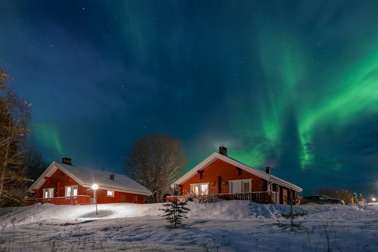 Cabanes en bois rouge sous les aurores boréales éclatantes d'un paysage finlandais